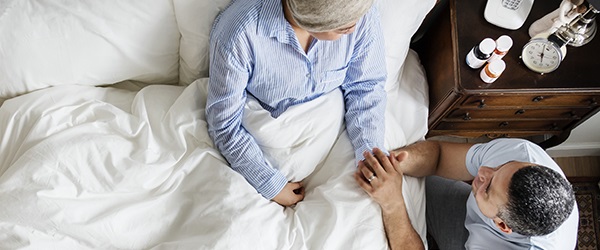 Man holding woman in bed's hand